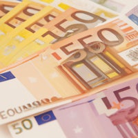 a stack of euro banknotes on a white surface